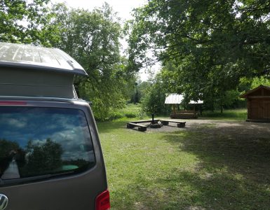 Bulli mit aufgestelltem Hochdach auf Campingsite mit Feuerstelle und Wasserzugang Somoo NP